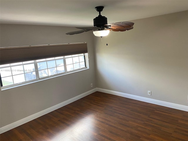 empty room with dark hardwood / wood-style flooring, vaulted ceiling, and ceiling fan