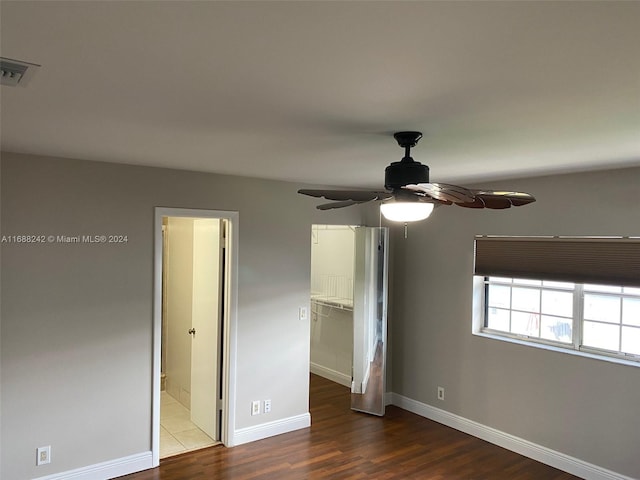 unfurnished bedroom featuring ceiling fan, wood-type flooring, a walk in closet, and a closet