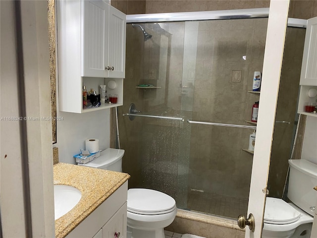 bathroom featuring a shower with door, vanity, and toilet