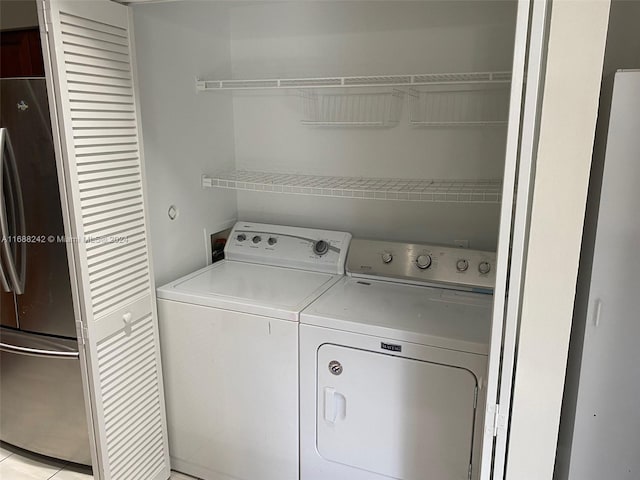 clothes washing area featuring washing machine and dryer and light tile patterned floors