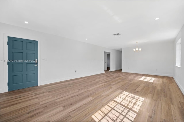 spare room with light hardwood / wood-style floors and a notable chandelier