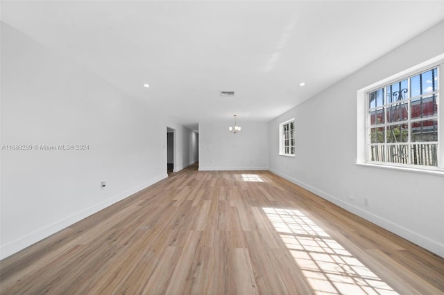 unfurnished living room featuring light hardwood / wood-style flooring and a chandelier