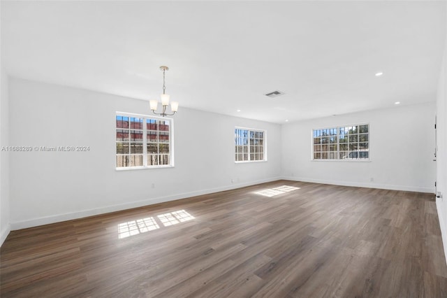 unfurnished room with a notable chandelier, dark wood-type flooring, and a wealth of natural light