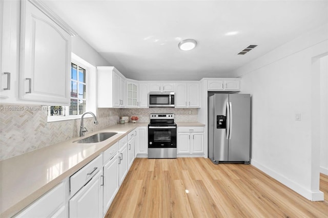 361 E 39th St, Hialeah, FL 33013 - kitchen featuring stainless steel appliances, tasteful backsplash, light wood finished floors, glass insert cabinets, and white cabinetry