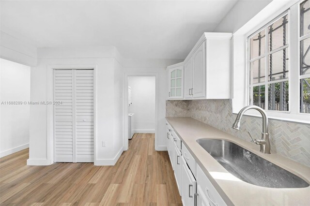 361 E 39th St, Hialeah, FL 33013 - kitchen featuring white cabinets, backsplash, light countertops, and light wood-style flooring
