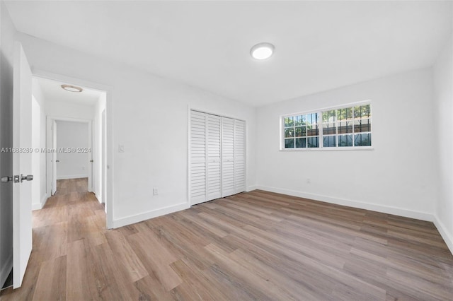 unfurnished bedroom with light hardwood / wood-style floors and a closet