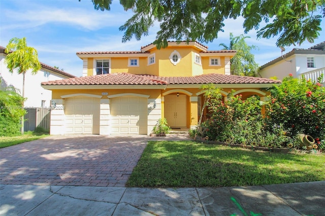mediterranean / spanish home featuring a garage, stucco siding, a front yard, a tiled roof, and decorative driveway