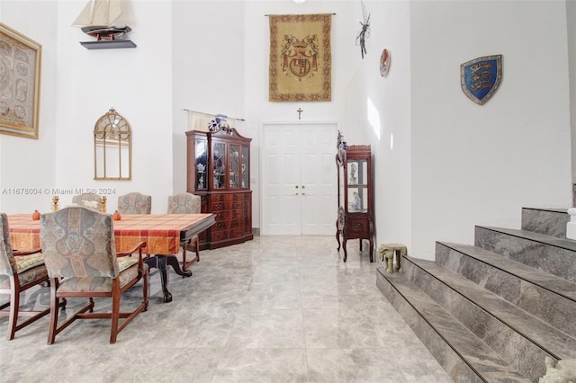 interior space featuring marble finish floor, stairway, and a high ceiling