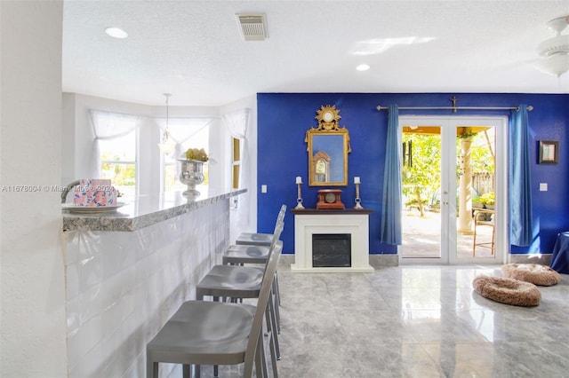 living room featuring ceiling fan, plenty of natural light, a textured ceiling, and french doors