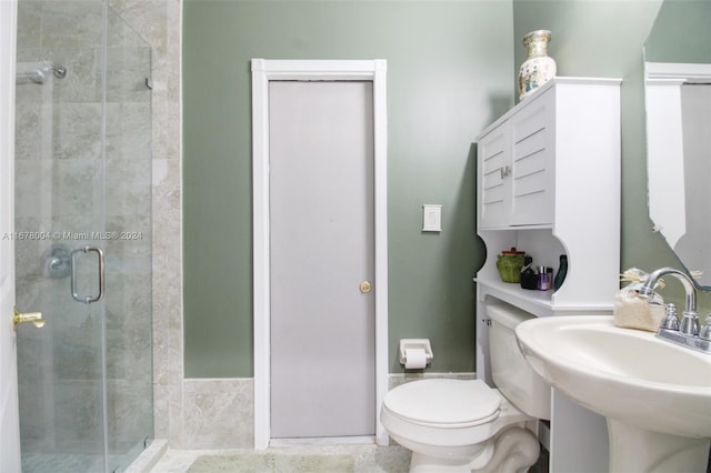 bathroom featuring sink, toilet, and a shower with shower door