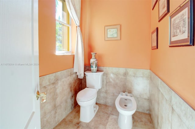 bathroom featuring a bidet, tile patterned flooring, toilet, and tile walls