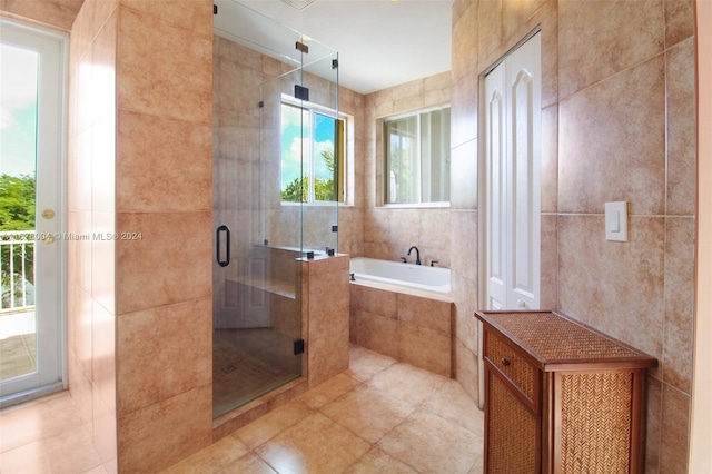 full bathroom featuring tile walls, a bath, tile patterned flooring, and a stall shower