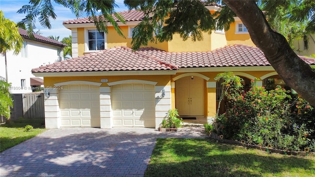 mediterranean / spanish house featuring an attached garage, stucco siding, a tile roof, and decorative driveway
