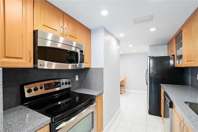 kitchen featuring stainless steel appliances, light tile patterned floors, light stone counters, and backsplash