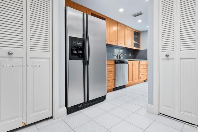 kitchen with light brown cabinetry, light tile patterned floors, backsplash, and appliances with stainless steel finishes