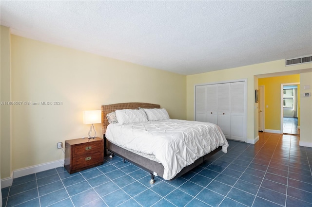 bedroom featuring a textured ceiling, dark tile patterned flooring, and a closet