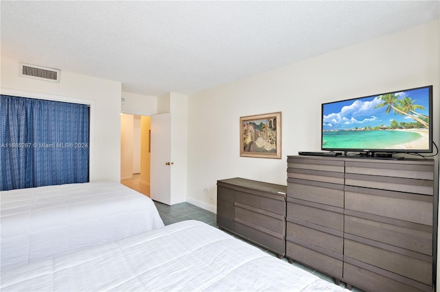 bedroom featuring dark tile patterned flooring and a textured ceiling