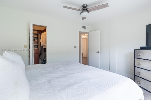 bedroom with a closet, a spacious closet, hardwood / wood-style flooring, and ceiling fan