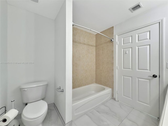 bathroom with tiled shower / bath combo and toilet