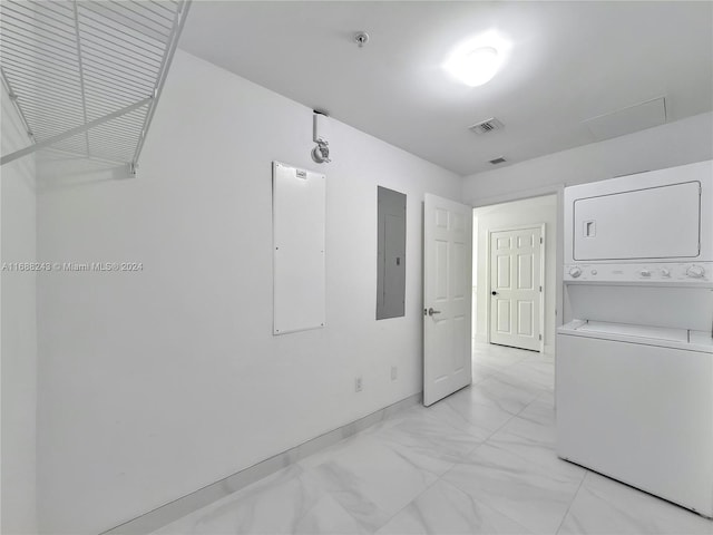 laundry area with electric panel and stacked washer and clothes dryer