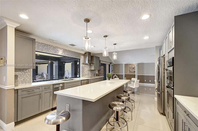 kitchen featuring tasteful backsplash, pendant lighting, gray cabinets, a kitchen island, and a breakfast bar area