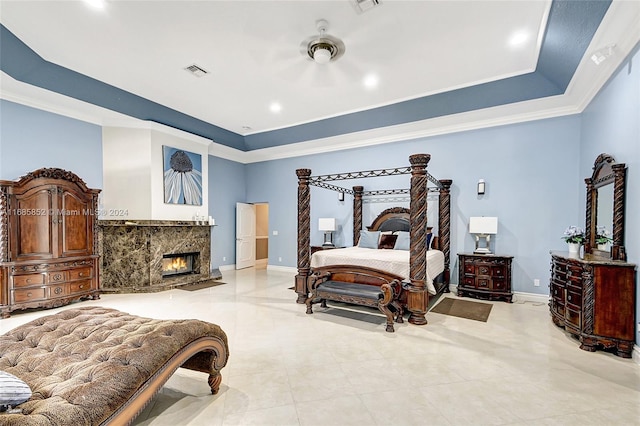 bedroom featuring a tray ceiling, crown molding, and a high end fireplace