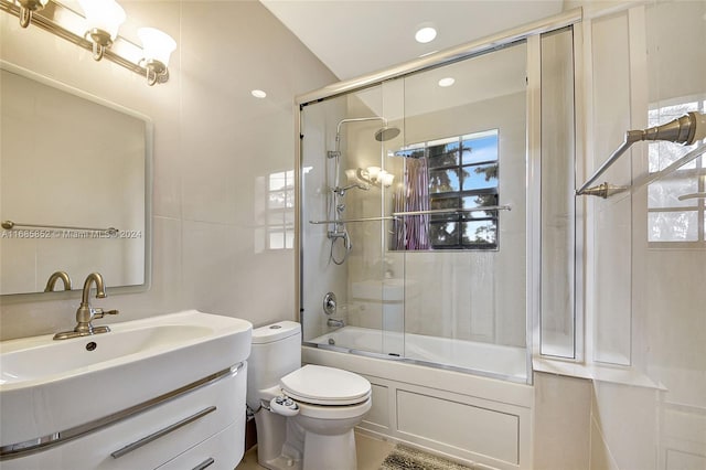 full bathroom with vanity, toilet, a healthy amount of sunlight, and bath / shower combo with glass door