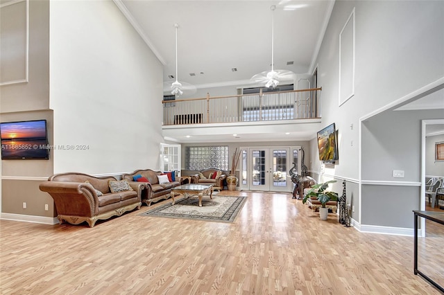 living room featuring a high ceiling, french doors, crown molding, light hardwood / wood-style flooring, and ceiling fan