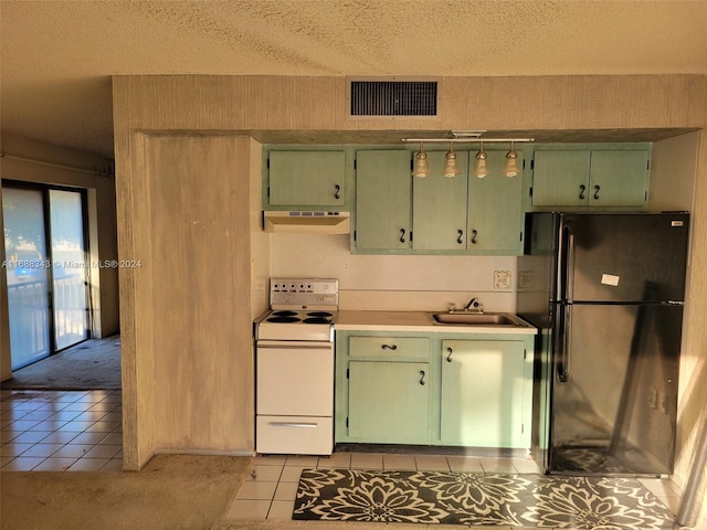 kitchen featuring sink, black fridge, white range, green cabinetry, and range hood