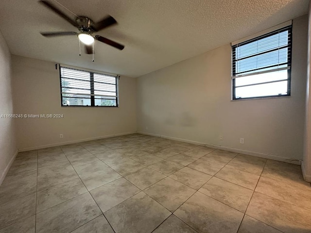 tiled spare room featuring a textured ceiling and ceiling fan