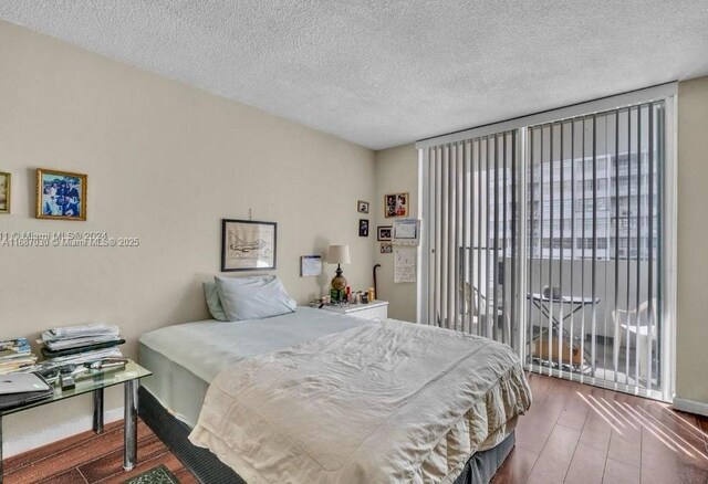 bedroom with multiple windows, hardwood / wood-style floors, floor to ceiling windows, and access to exterior