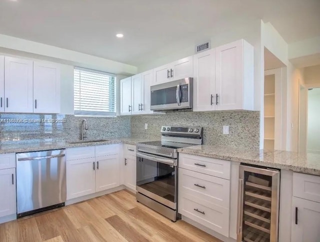 kitchen featuring wine cooler, appliances with stainless steel finishes, decorative backsplash, sink, and white cabinets