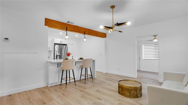 kitchen featuring white cabinetry, pendant lighting, stainless steel fridge, and light hardwood / wood-style flooring