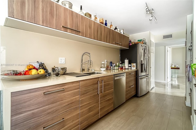 kitchen with appliances with stainless steel finishes, sink, and light hardwood / wood-style flooring