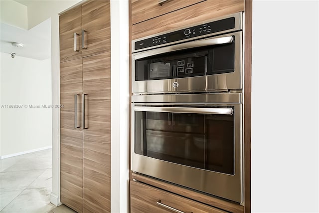 kitchen with stainless steel double oven and light tile patterned flooring