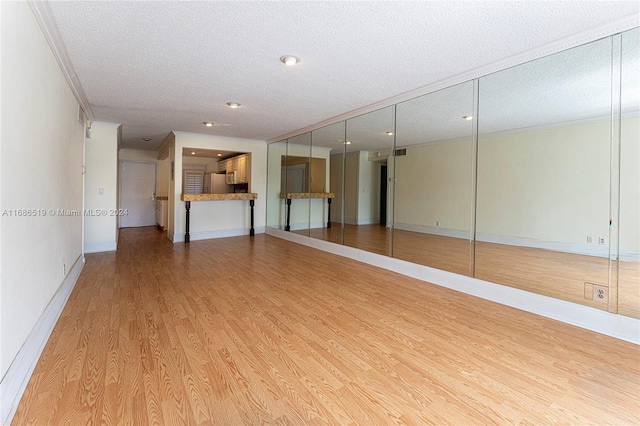 unfurnished living room featuring a textured ceiling, hardwood / wood-style flooring, and crown molding