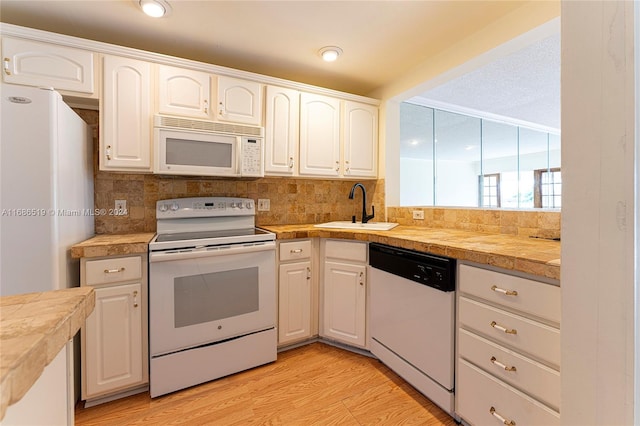 kitchen featuring white cabinetry, sink, light hardwood / wood-style floors, and white appliances