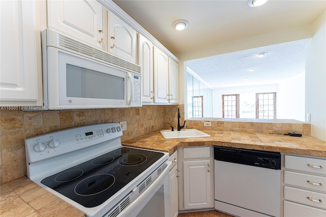 kitchen with white appliances, white cabinets, sink, light tile patterned floors, and tasteful backsplash