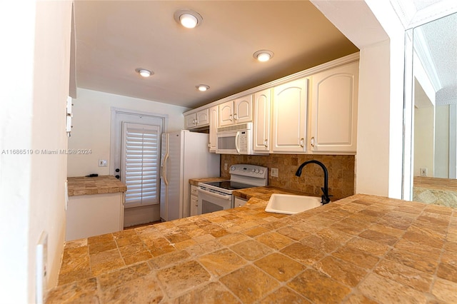 kitchen with white cabinets, decorative backsplash, white appliances, and sink