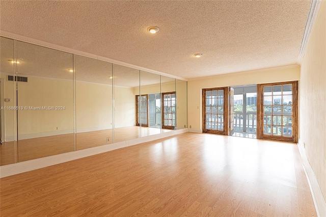 spare room with wood-type flooring, a textured ceiling, and crown molding