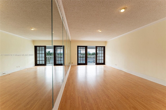 empty room featuring french doors, wood-type flooring, a textured ceiling, and ornamental molding