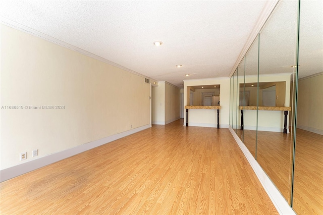 spare room with hardwood / wood-style flooring, crown molding, and a textured ceiling