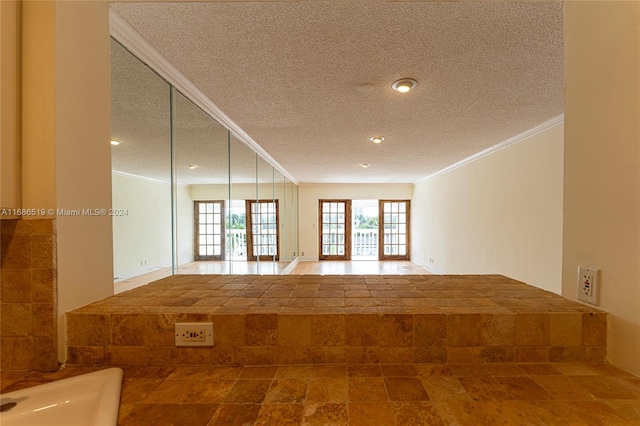 spare room with french doors, a textured ceiling, and crown molding