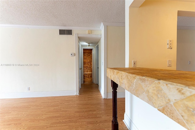 corridor featuring a textured ceiling, hardwood / wood-style flooring, and crown molding