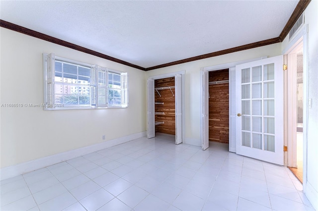 unfurnished bedroom with a textured ceiling, two closets, and ornamental molding