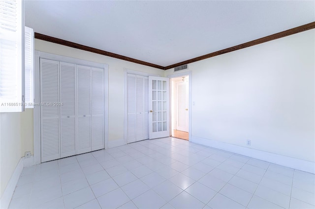 unfurnished bedroom with crown molding and two closets