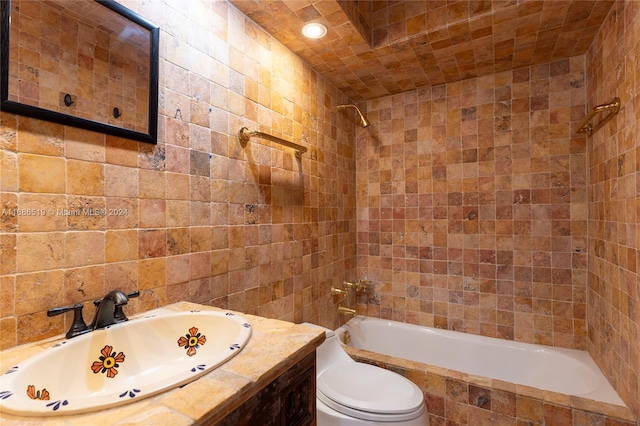 full bathroom with tile walls, vanity, tiled shower / bath combo, and toilet