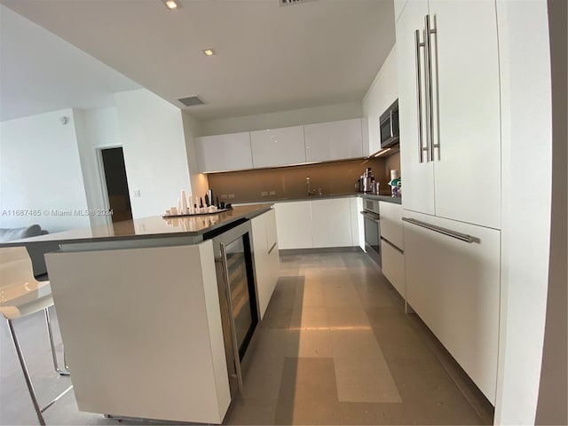 kitchen featuring white cabinets, wine cooler, a kitchen island, and stainless steel appliances