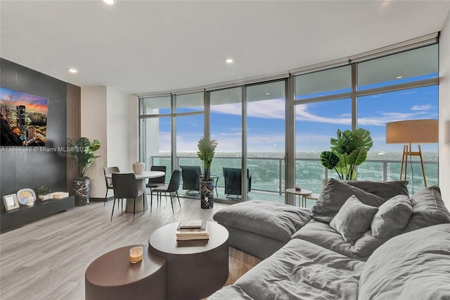 living room with hardwood / wood-style floors, a wall of windows, and a water view