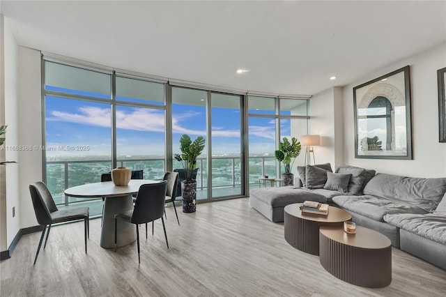 living room featuring a wall of windows, a water view, and light wood-type flooring